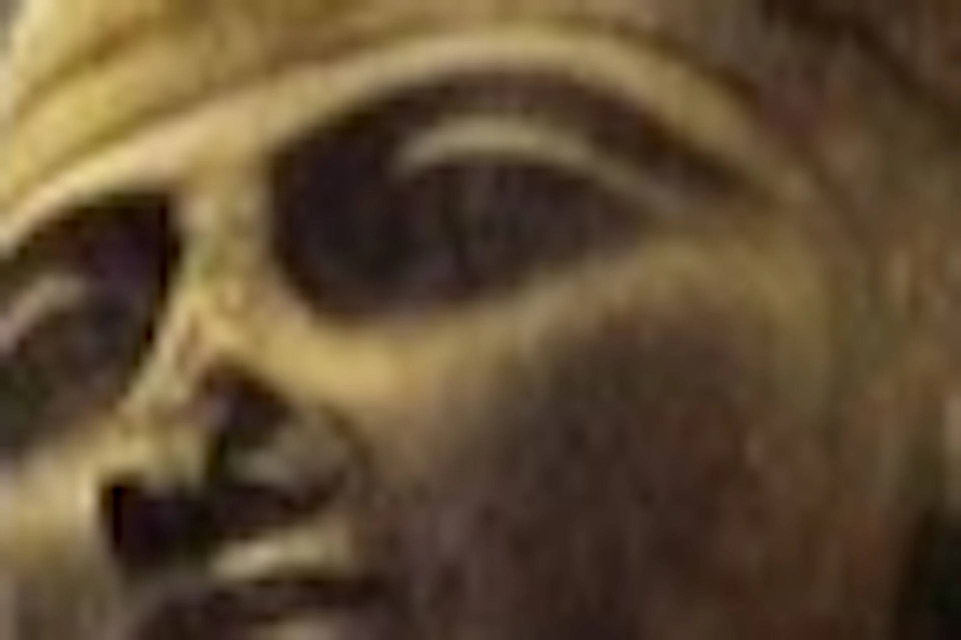 A large statue of an ancient Egyptian figure stands in a modern indoor space with a high ceiling and glass walls.