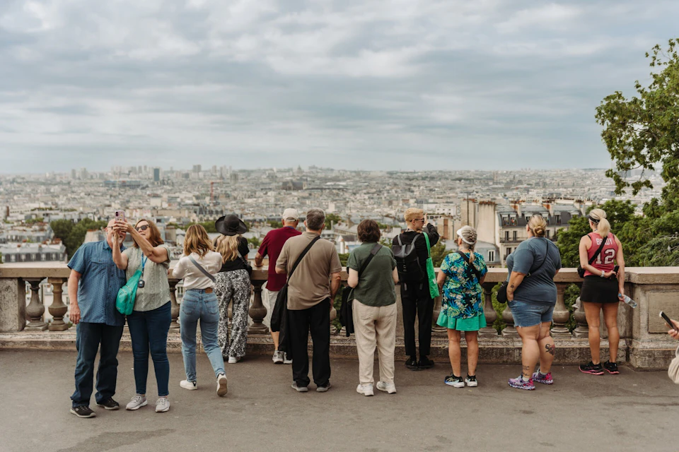 A group of people standing on a terrace overlooking a cityscape under a cloudy sky.