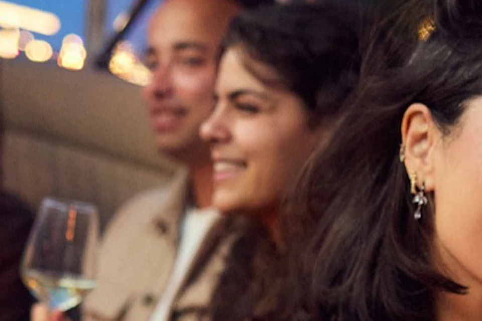 A group of people sitting together on a boat, with a man and woman in the foreground smiling and taking a selfie.