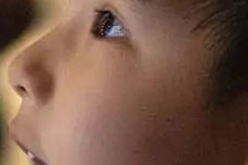A young boy looks up in awe at a large, detailed prop resembling a creature, in a room filled with decorative lights.