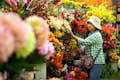 Een vrouw bekijkt een bloem op de beruchte bloemenmarkt van Bangkok