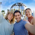Tourists taking a selfie in front of the Universal globe at the entrance of Universal Studios Hollywood