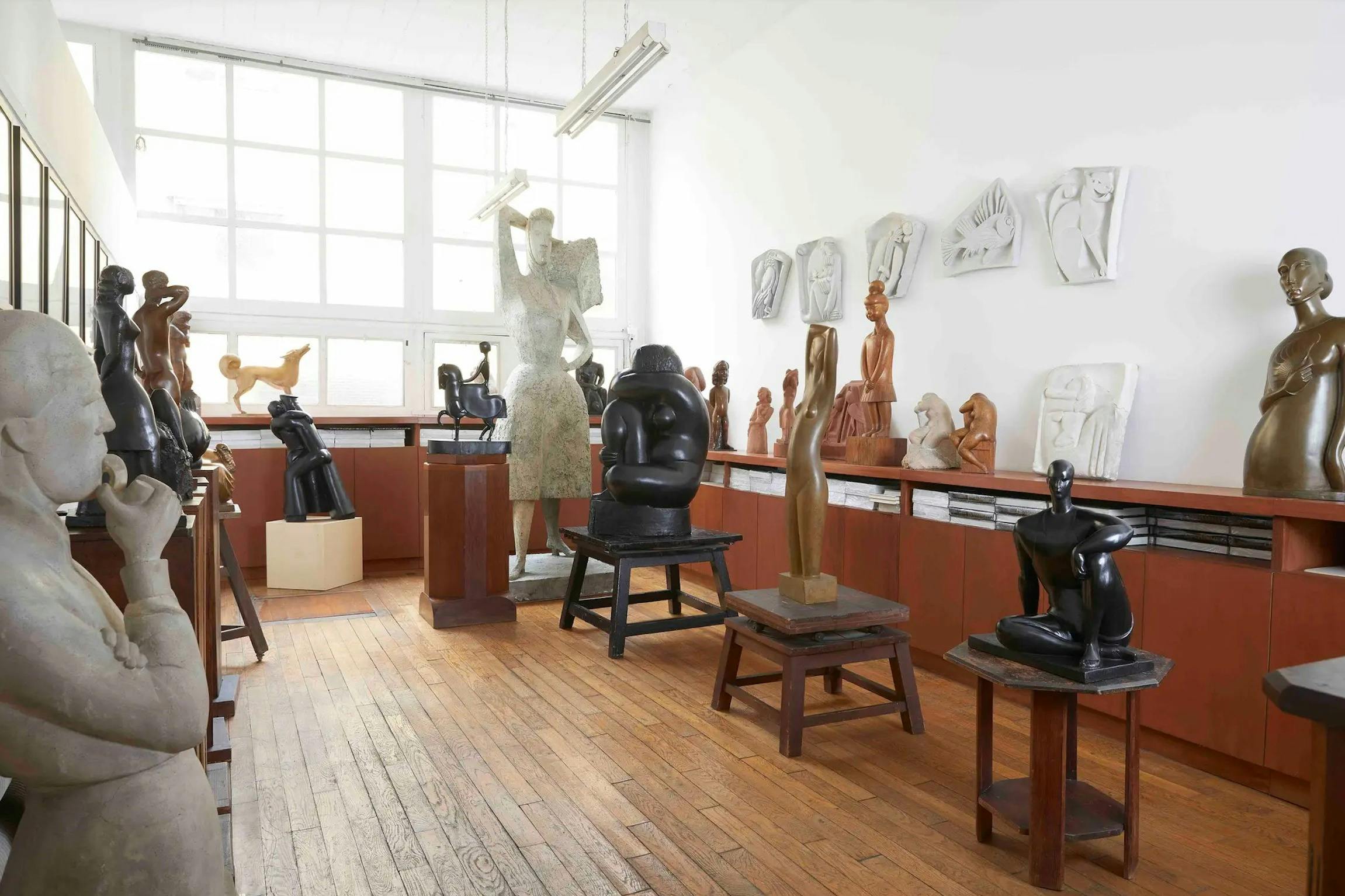 台座や棚に様々な彫刻が展示された部屋で、人間的で抽象的な形状が特徴で、明るい照明が施されています。