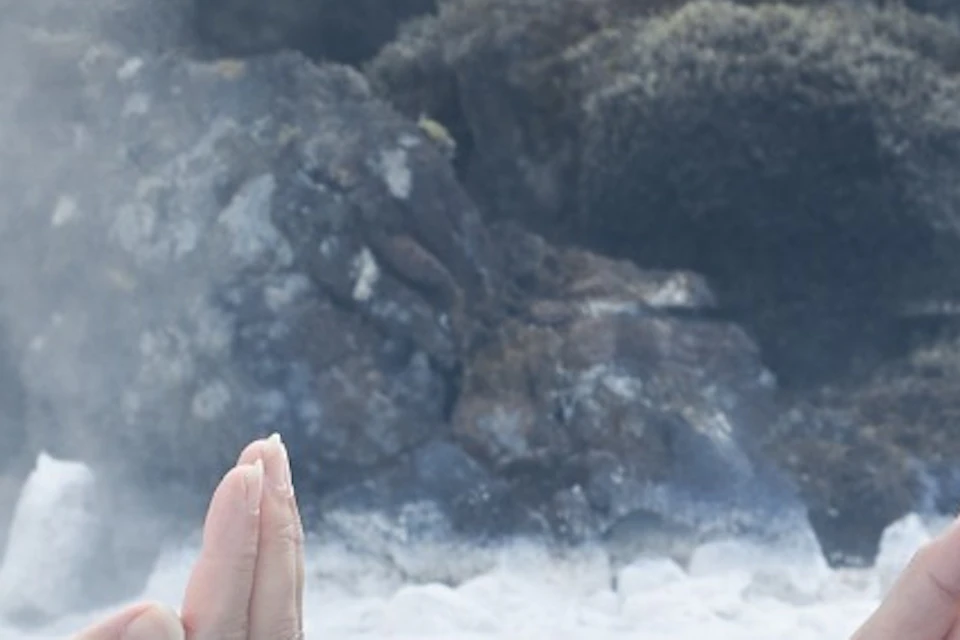 Women applying Silica Mud Mask surrounded by moss covered lava field in the Blue Lagoon