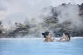 Women applying Silica Mud Mask surrounded by moss covered lava field in the Blue Lagoon 