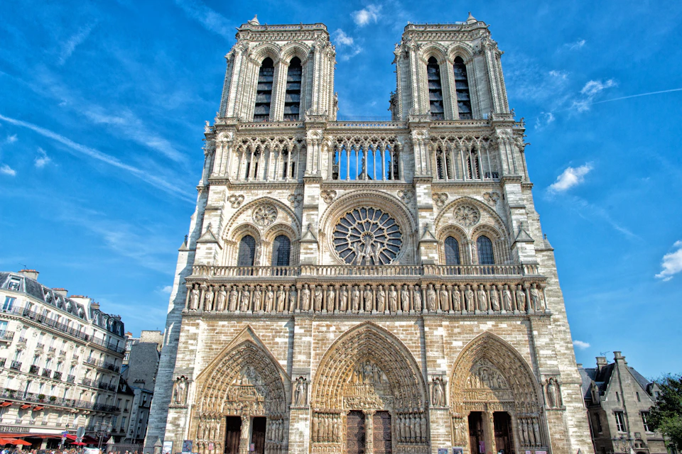 The facade of Notre-Dame Cathedral in Paris, featuring two towers, intricate stone carvings, and a large rose window.