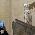 Eine Person, die mit ihrem Handy im Louvre-Museum ein Foto der Skulptur Nike von Samothrake macht
