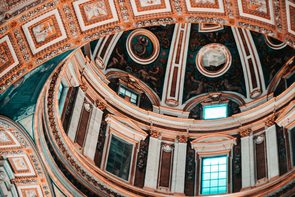 Ornate interior dome with detailed frescoes, intricate patterns, and arched windows, illuminated by natural light.