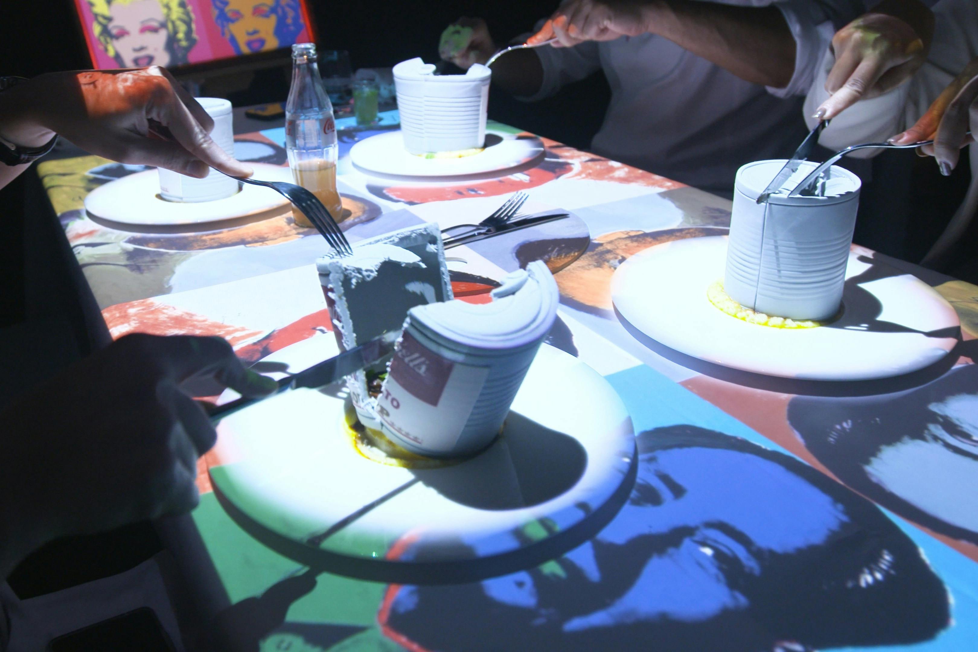 Οι επισκέπτες κόβουν σε φέτες ένα φαγώσιμο κουτάκι σούπας Warhol στην καθηλωτική επίδειξη φαγητού Seven Paintings.