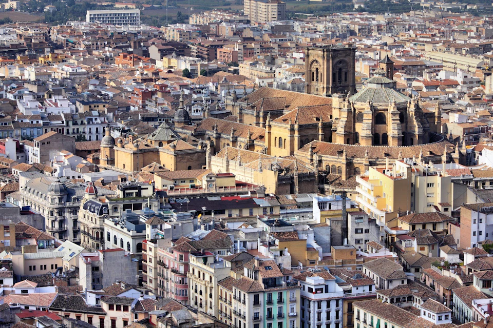 Aerial view of a historic city center with a prominent cathedral surrounded by densely packed buildings.