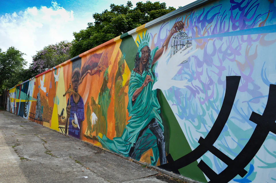Colorful mural featuring Statue of Liberty holding a birdcage, releasing a dove, with vibrant surrounding figures and nature elements.