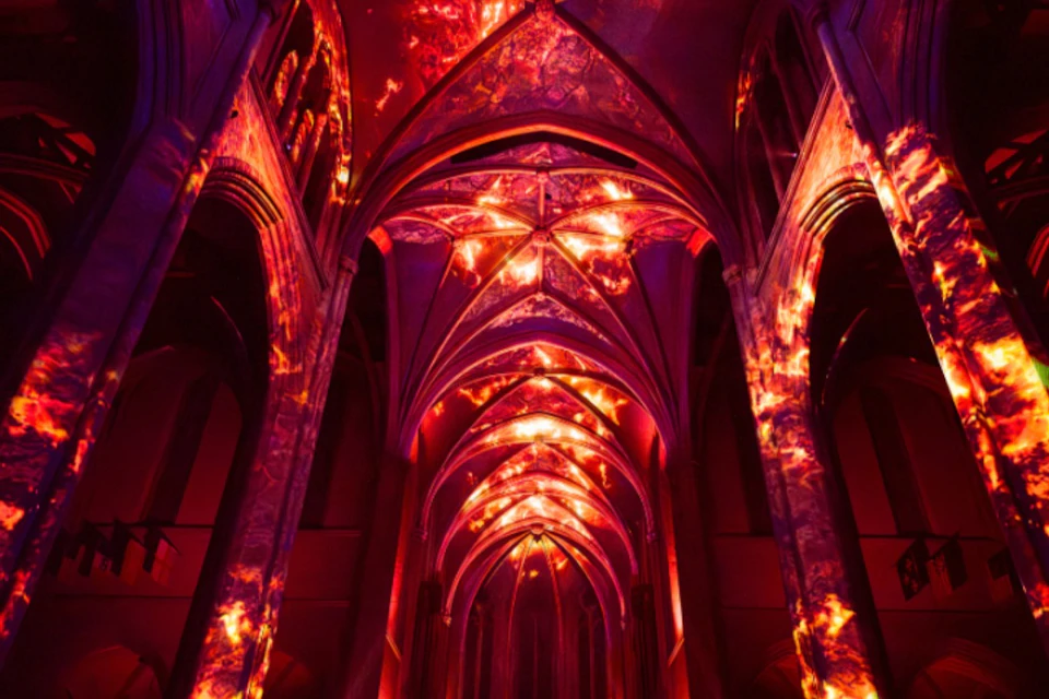 An illuminated cathedral ceiling with vibrant red and orange lighting effects creating a dramatic atmosphere.