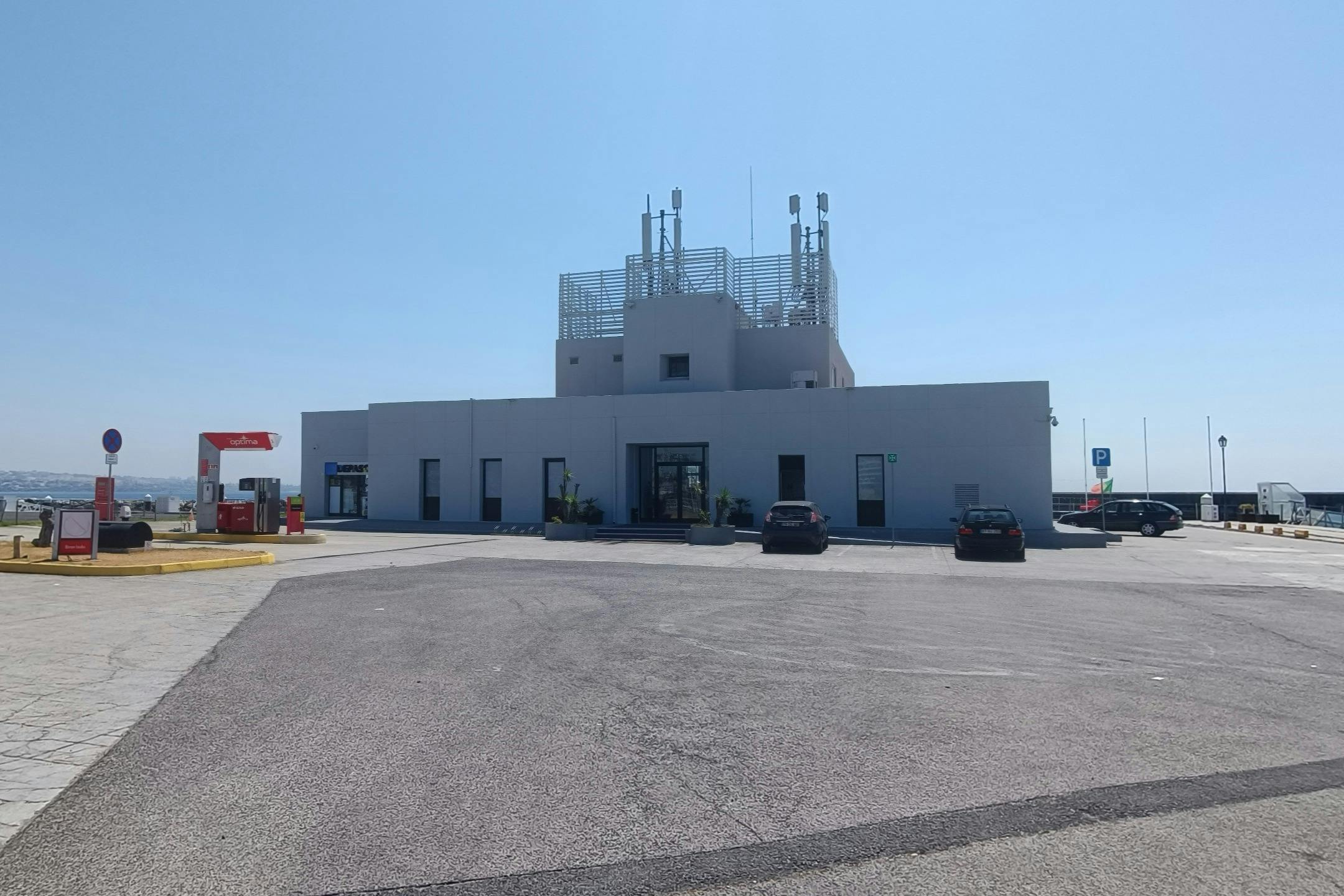 天気のいい日には、屋根にアンテナ、舗装された駐車場、前に駐車場が2台あるモダンな1階建ての白い建物です。