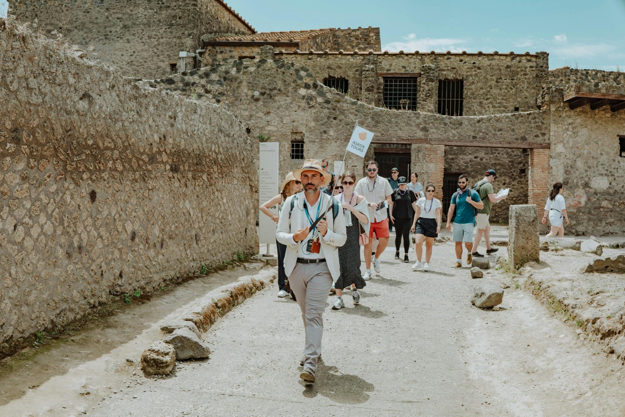 ツアーガイドは、澄んだ青い空の下、古代の石造りの遺跡を観光客のグループを案内します。