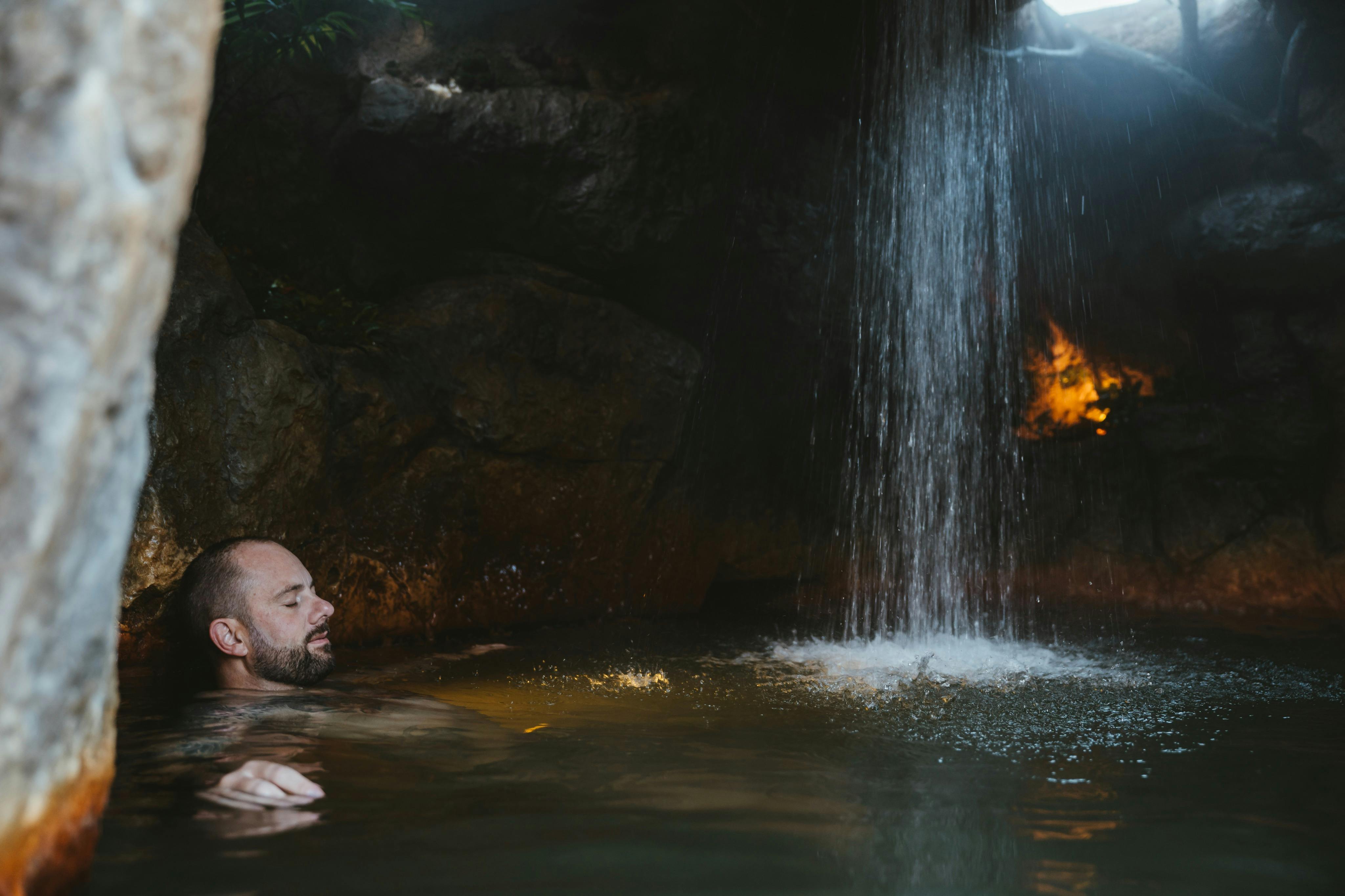 Uomo rilassato e immerso nelle acque geotermiche all'interno di una grotta