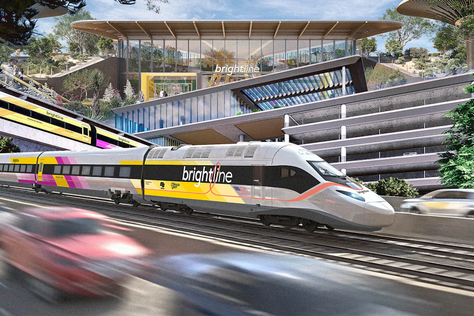 A bright yellow and white high-speed train labeled 'Brightline' passing in front of a modern station building with large windows.