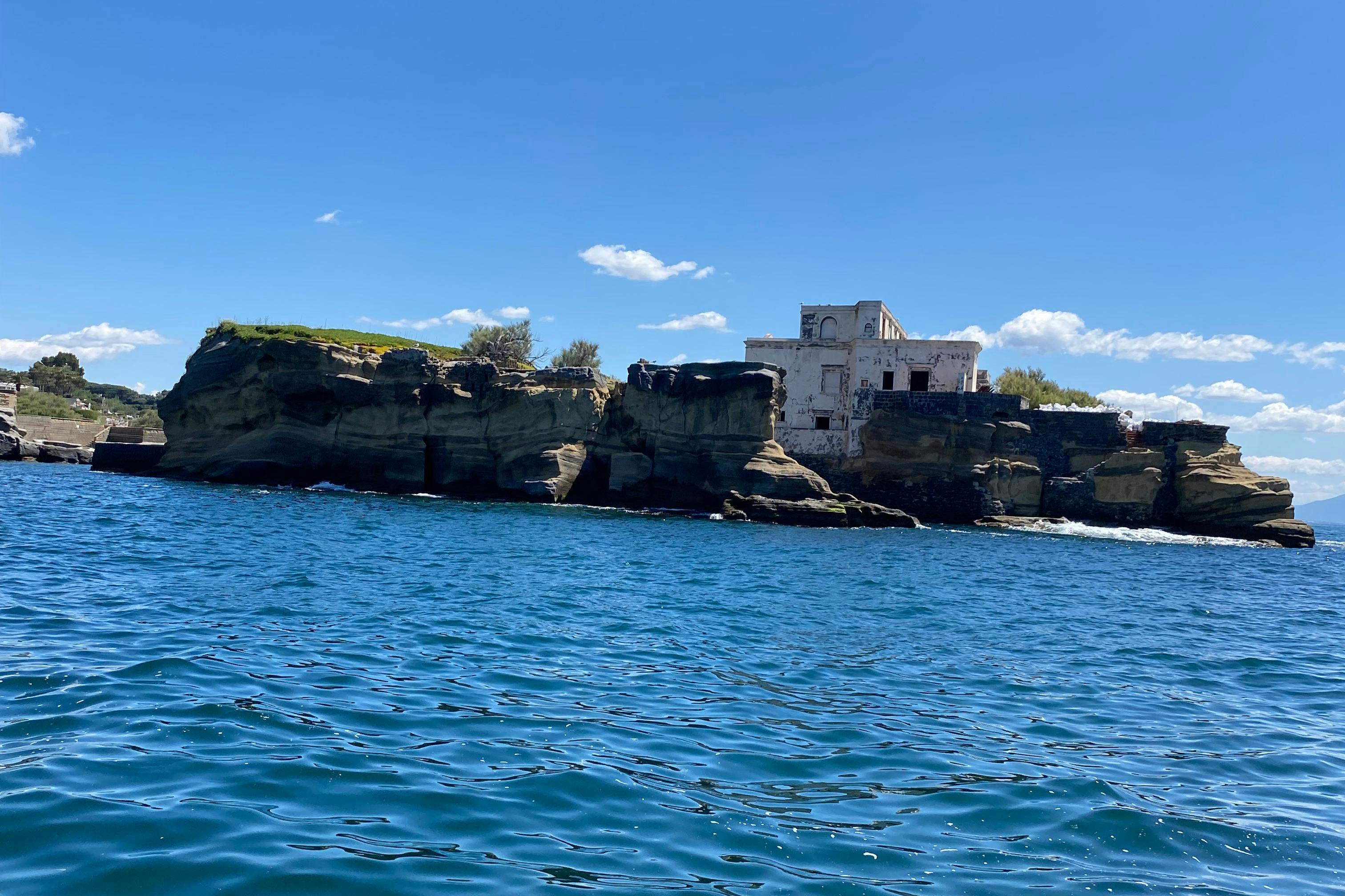 Edificio blanco en una costa rocosa contra un cielo azul claro y el agua azul vibrante del océano.