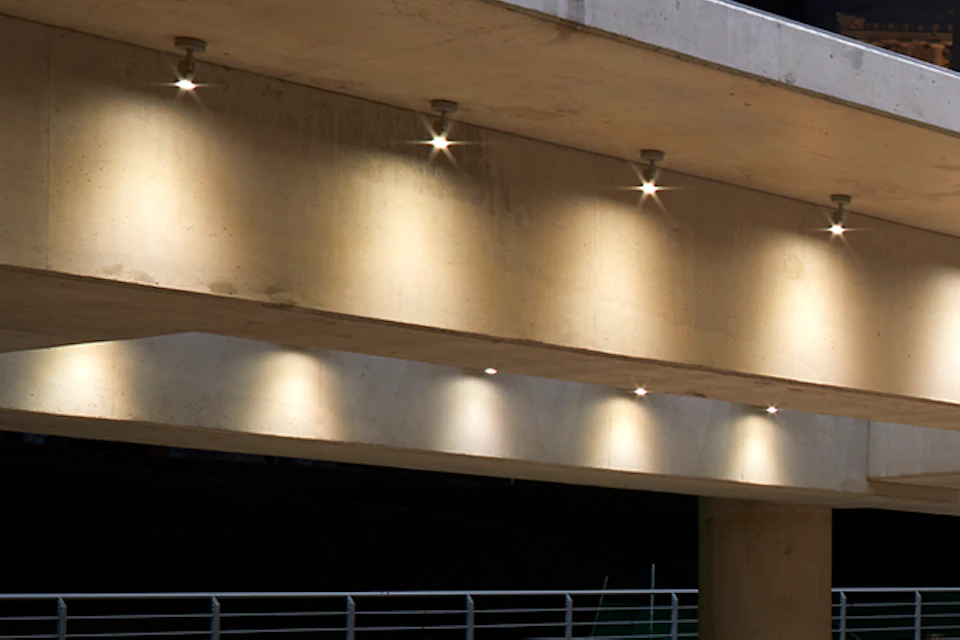 Archaeological ruins lit by modern overhead lighting, with a circular structure in the foreground and elevated walkways above.