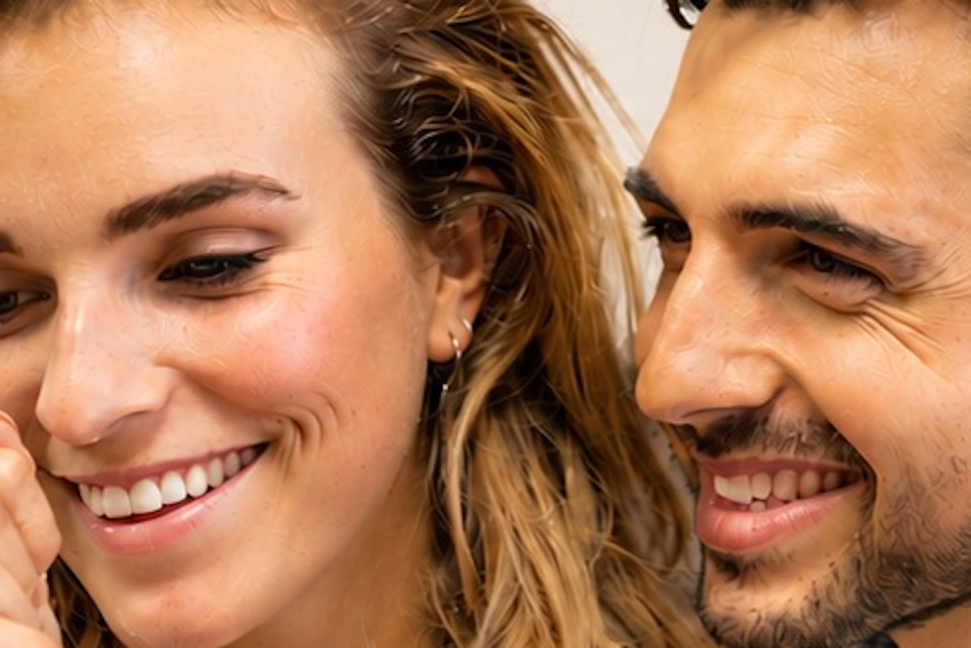 A woman and a man are smiling while the woman examines a diamond using a loupe. The background reads "Coster Diamonds."