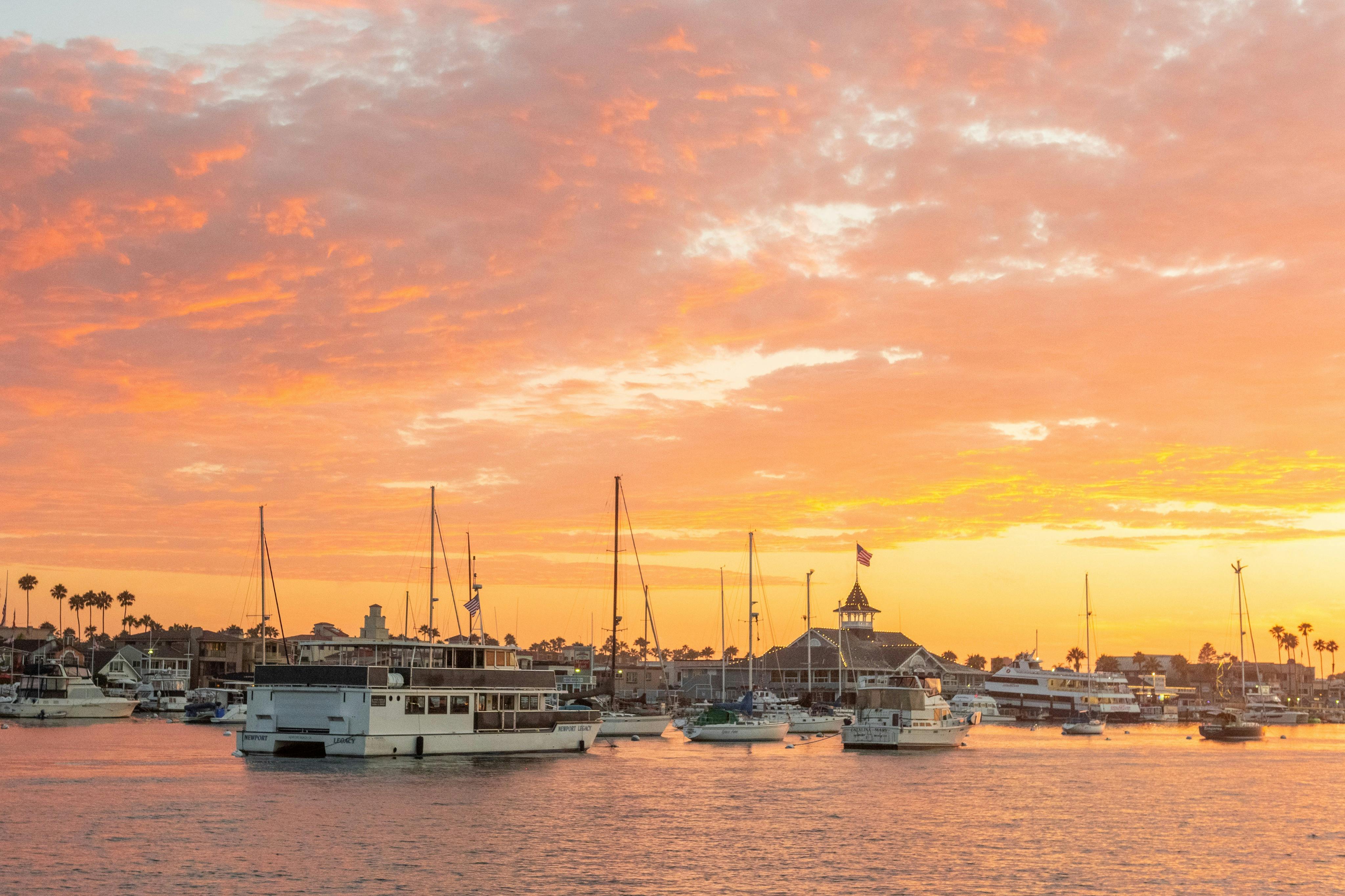 Blick auf den Sonnenuntergang in Newport Beach, unser maßgeschneidertes Schiff, die Newport Legacy, und den historischen Balboa Pavilion.