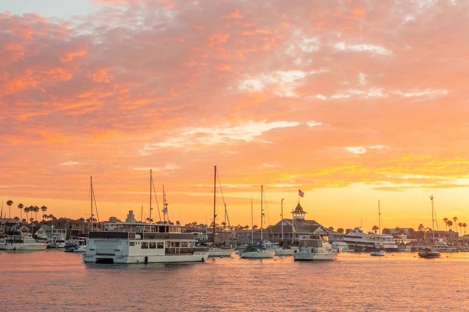 Looking at the sunset in Newport Beach, our custom-made ship, the Newport Legacy, and the historic Balboa Pavilion.