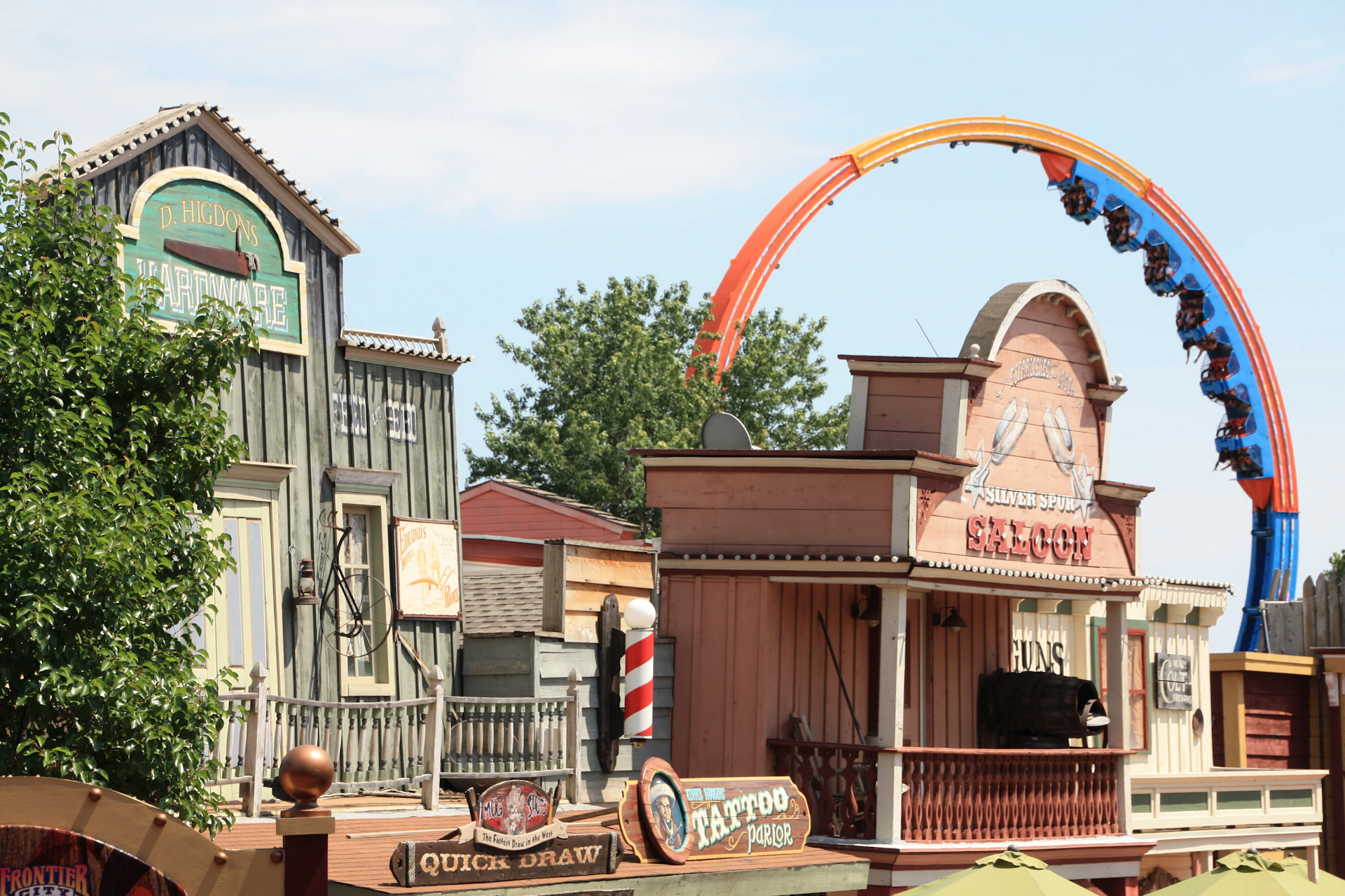 A western-themed amusement park area with saloon-style buildings and a colorful rollercoaster in the background.