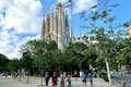 Uitzicht in de verte op de Sagrada Familia tussen de bomen van het aangrenzende park.