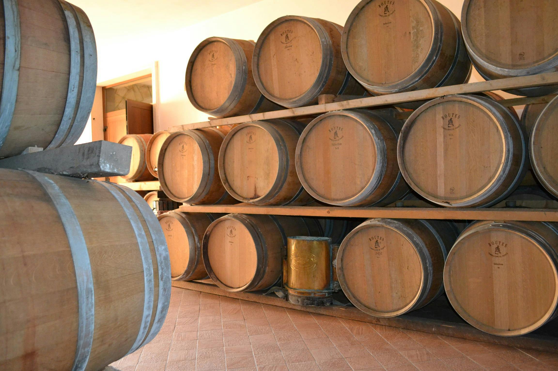 Una stanza con botti di legno impilate su rastrelliere, probabilmente utilizzate per conservare il vino o altre bevande.