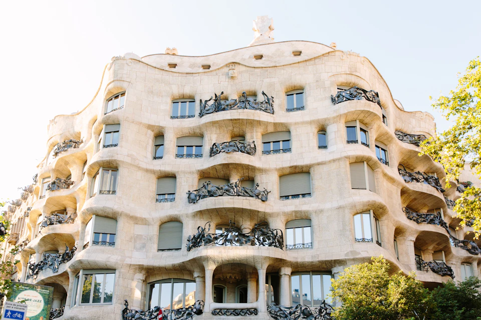 A unique, wavy facade building with intricate balconies and numerous windows, under a clear sky.