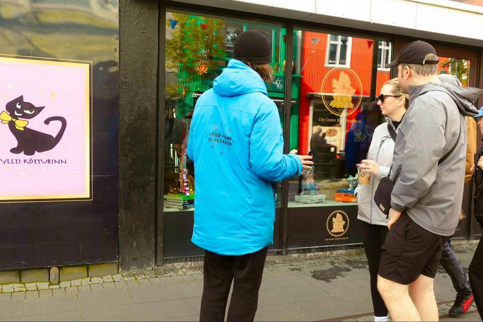 파란색 재킷을 입은 사람이 매장 밖에서 화려한 디스플레이와 창문에 비친 세 사람에게 말을 걸고 있습니다.