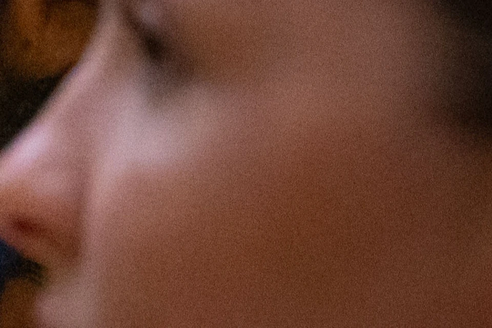 A blurred close-up of a woman in profile in front of a classical painting featuring mythological figures in a landscape.