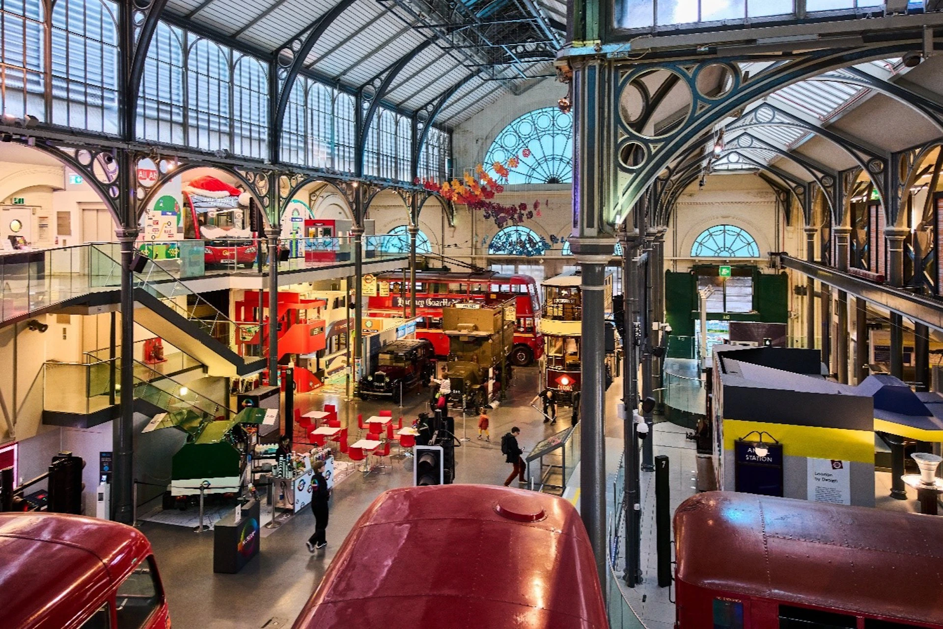 An indoor exhibition space with vintage buses, historical vehicles, and visitors exploring the displays under an arched roof.