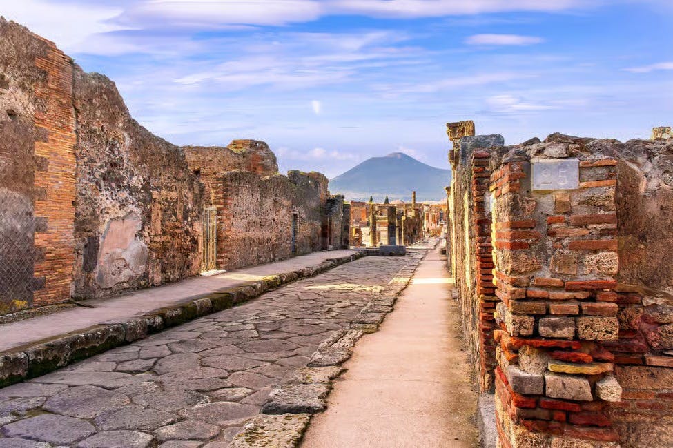 古遗址，石铺街道，蓝天下的墙壁被侵蚀，背景可见一座遥远的山脉。