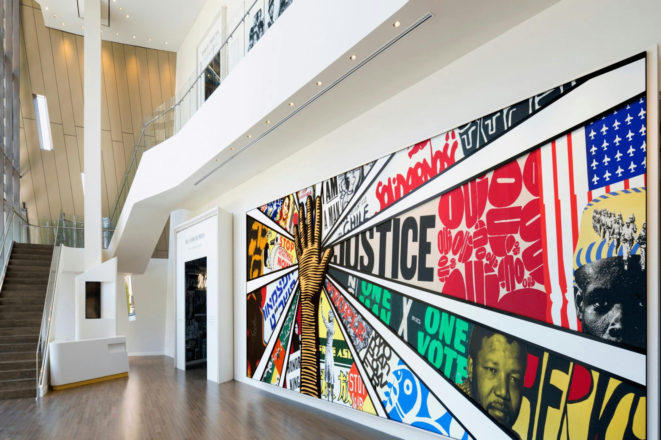 Um espaço interior moderno com um mural colorido que representa mensagens de justiça e igualdade, com gráficos e textos arrojados.