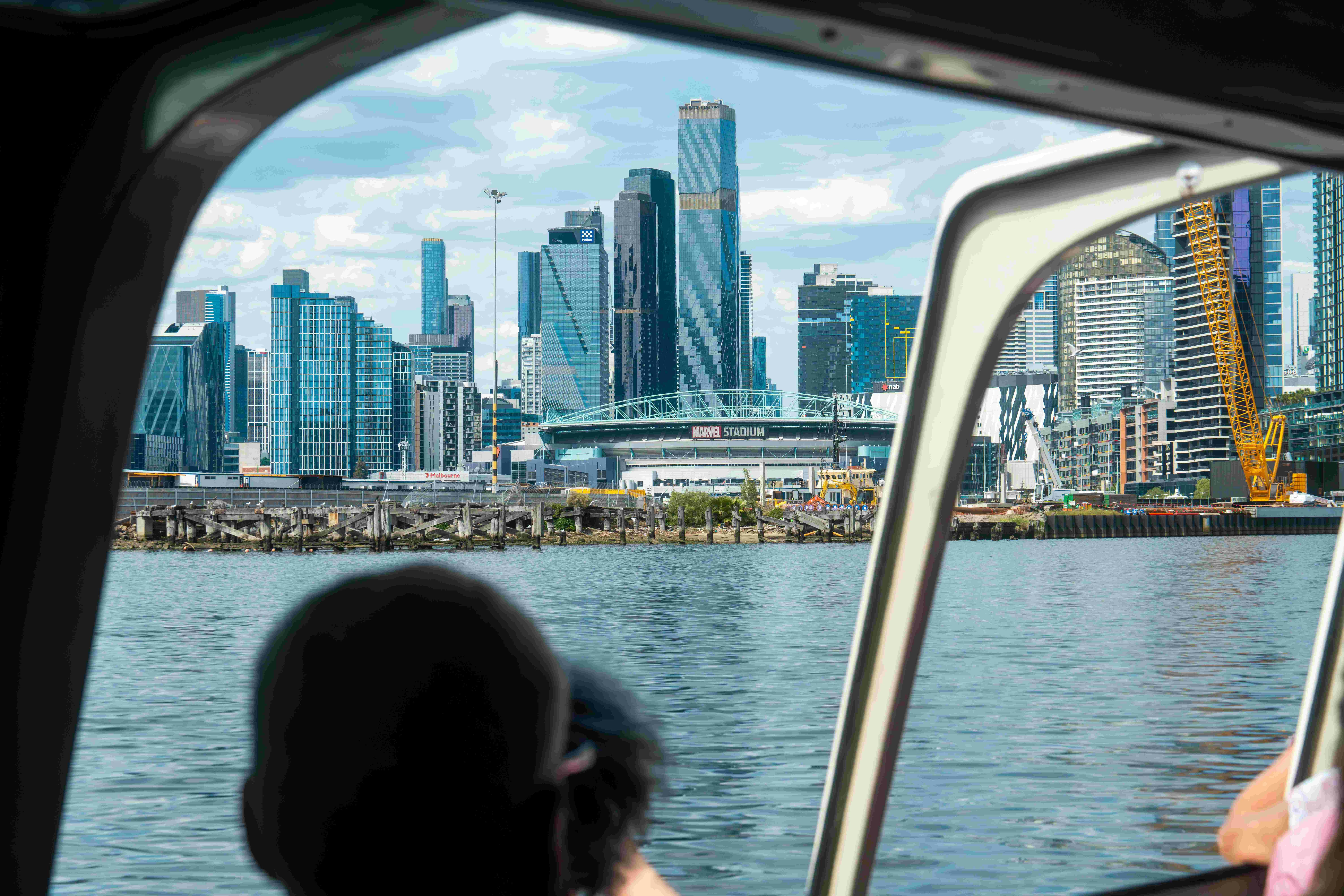 Pohled na panorama města s vysokými budovami a stadionem Marvel, který je vidět zevnitř lodi s rozostřeným člověkem v popředí.