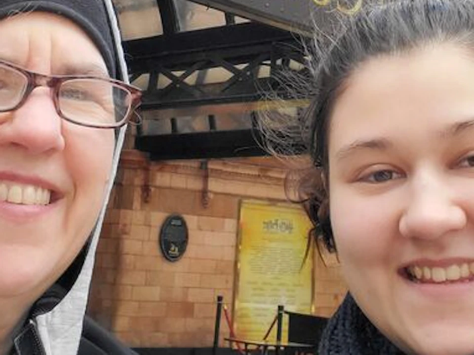 Two people smiling in front of the "Harry Potter and the Cursed Child" theater entrance.