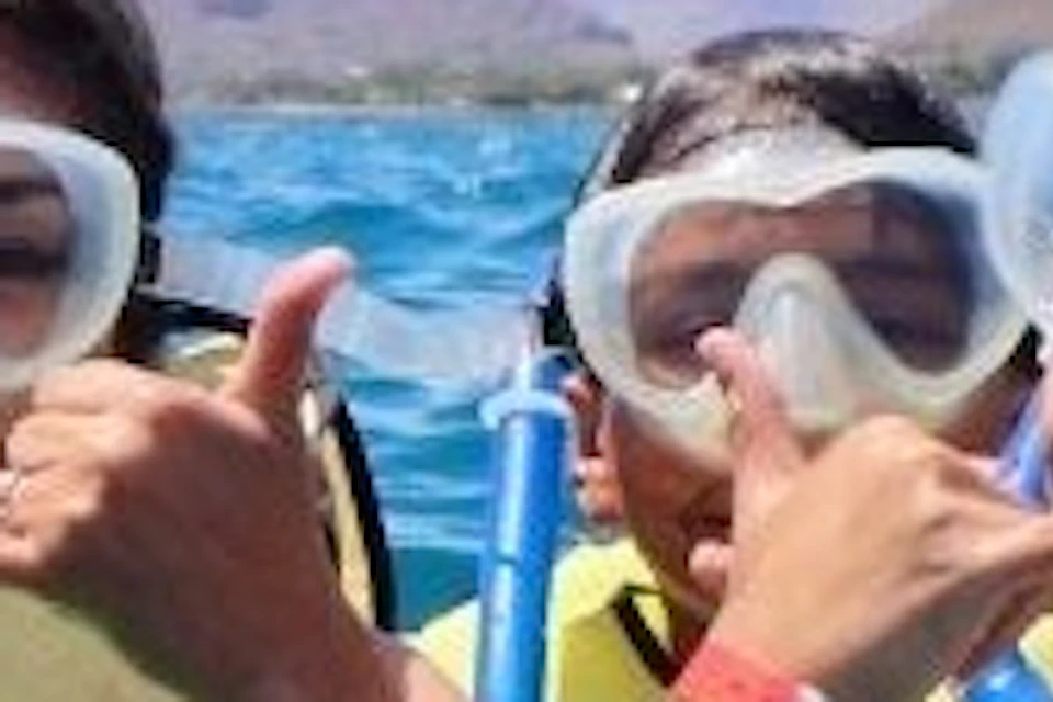 A group of four people in snorkeling gear and life vests giving thumbs up while floating in clear blue ocean water.