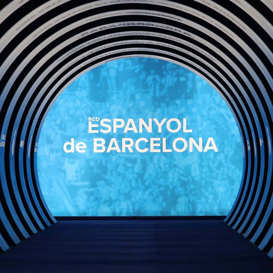 Curved tunnel structure with a lit blue end wall displaying the text "RCD ESPANYOL de BARCELONA."