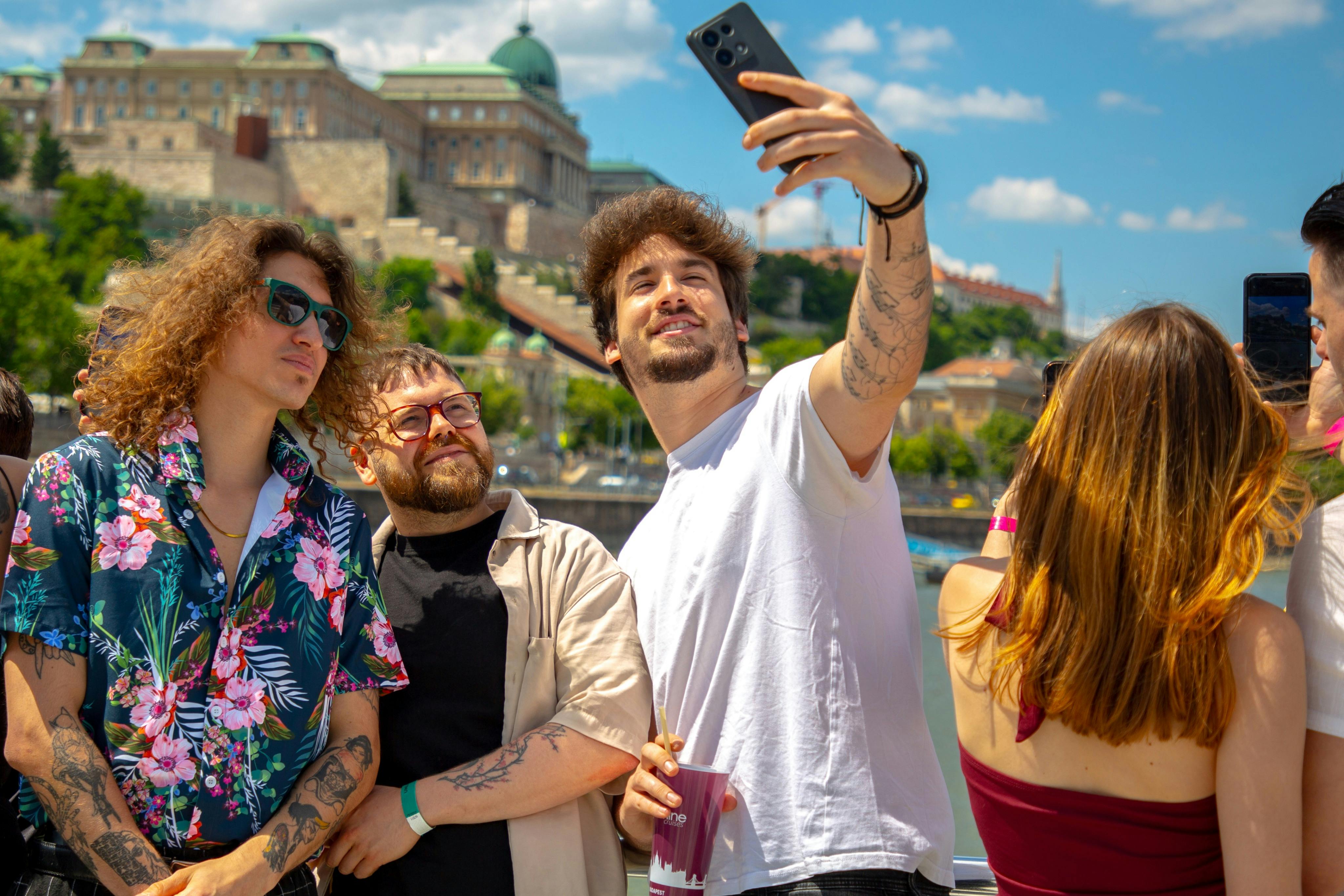 Drei Freunde machen an einem sonnigen Tag ein Selfie im Freien mit einem historischen Gebäude im Hintergrund.