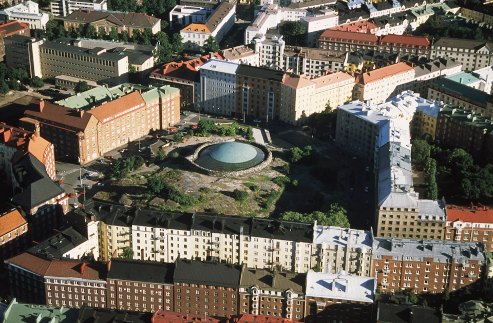 Aerial view of a city area featuring a large, circular building with a dome roof surrounded by residential buildings.