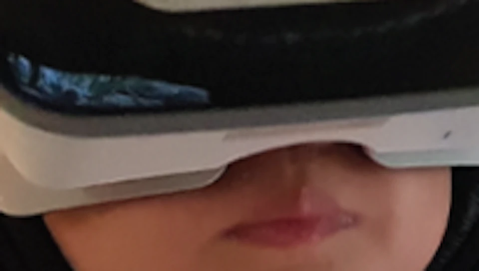 Child wearing a virtual reality headset with a wolf face design and headphones, seated indoors. Background shows a nature poster.