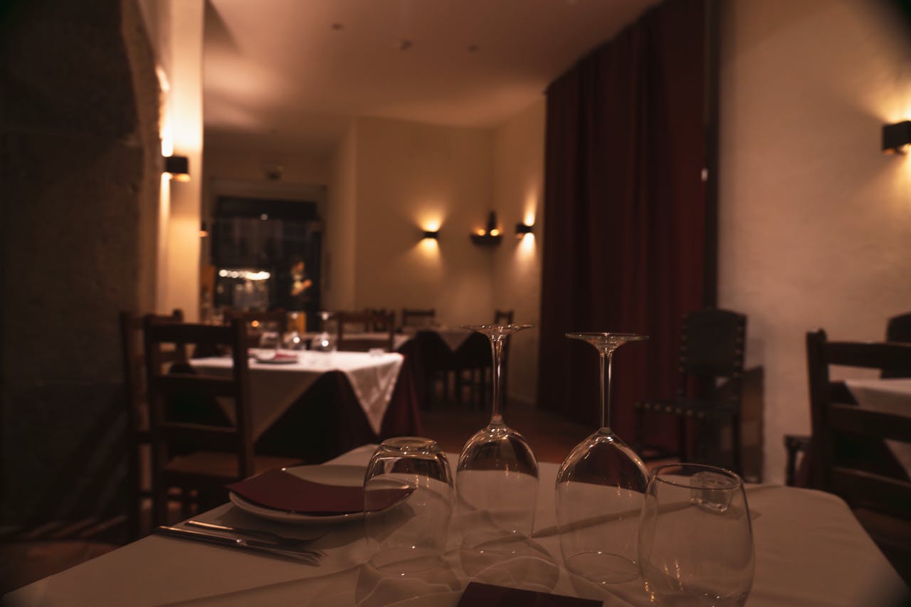 空のテーブル、白いテーブルクロス、ワイングラス、エレガントな雰囲気の薄暗いレストラン。