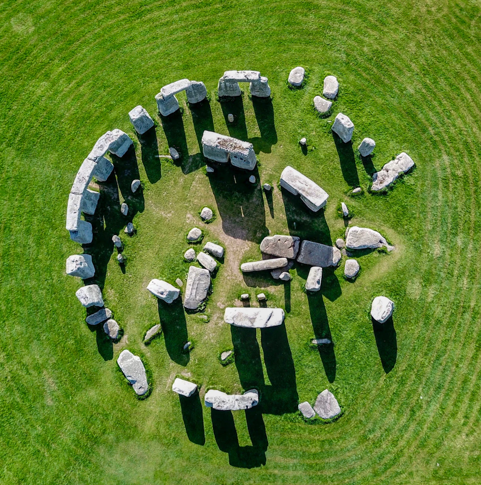 An aerial view of Stonehenge, showing its circular arrangement of large standing stones on a grassy field.