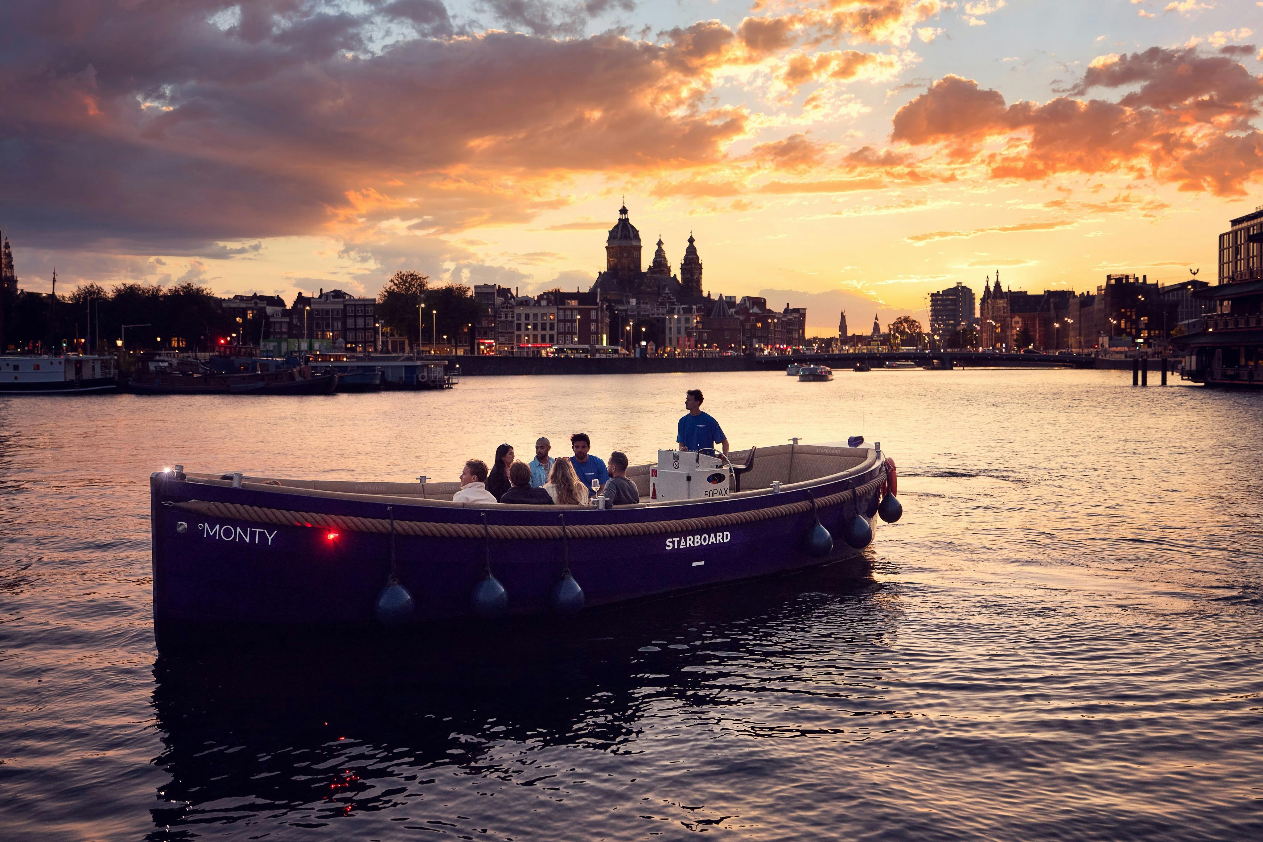 街のスカイラインと塔を背景に、夕暮れ時に川に乗客を乗せたボート。