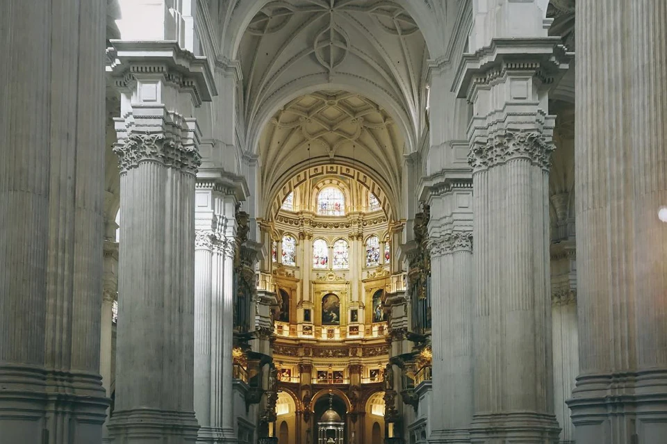 Interior of a grand cathedral with intricate columns, stained glass windows, and decorative arches.