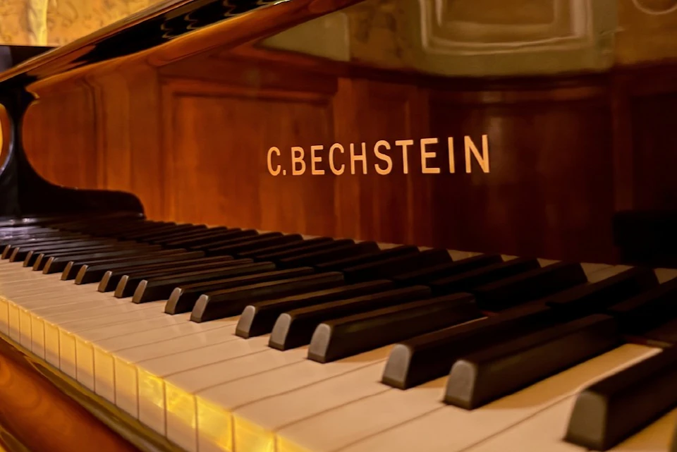 Close-up of a C. Bechstein piano keyboard and part of the wooden body with the brand logo prominently displayed.