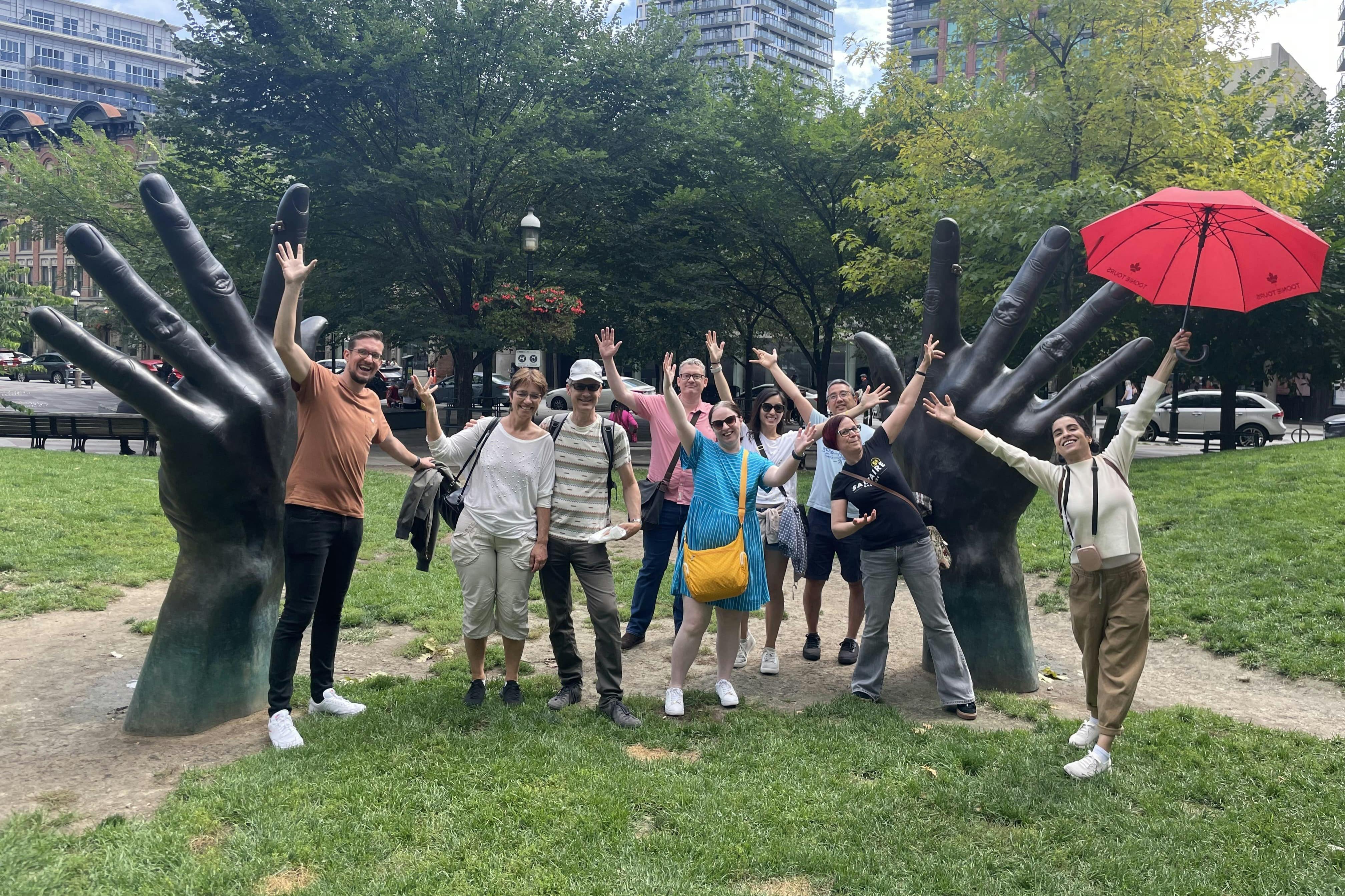 一群人在公园里摆出大型手工雕塑，背景是树木和建筑物。