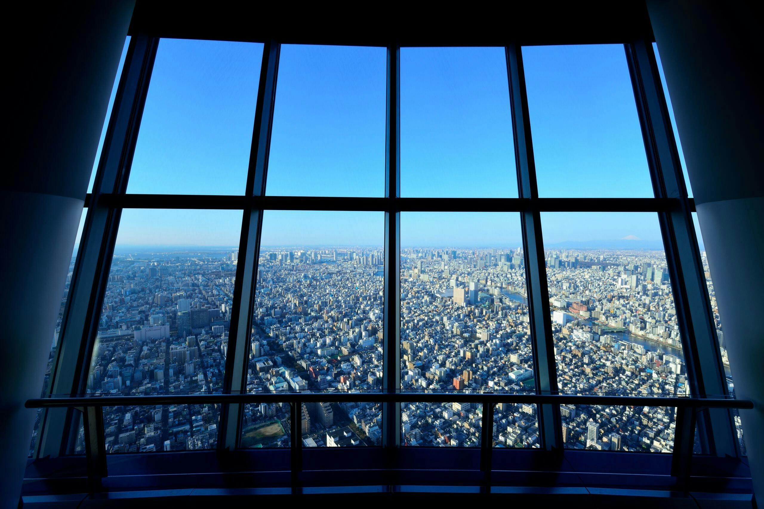 鸟瞰高楼层的大窗户，透过晴朗的蓝天，可以看到拥挤的城市景观。
