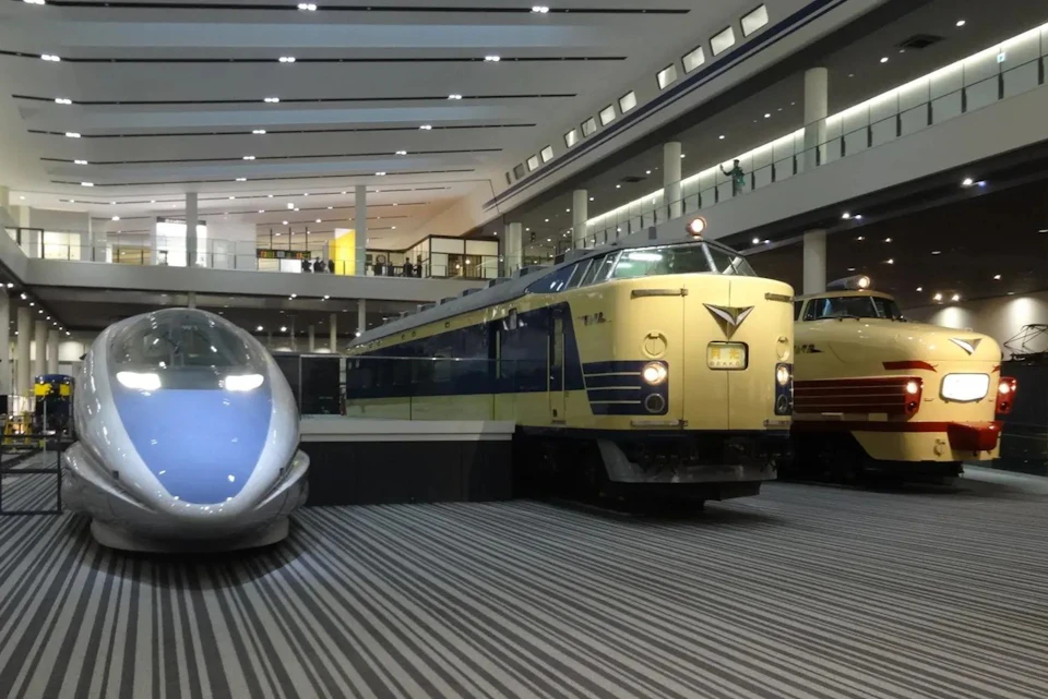 A museum exhibit featuring vintage trains, including a blue and white train and a yellow train, displayed indoors.