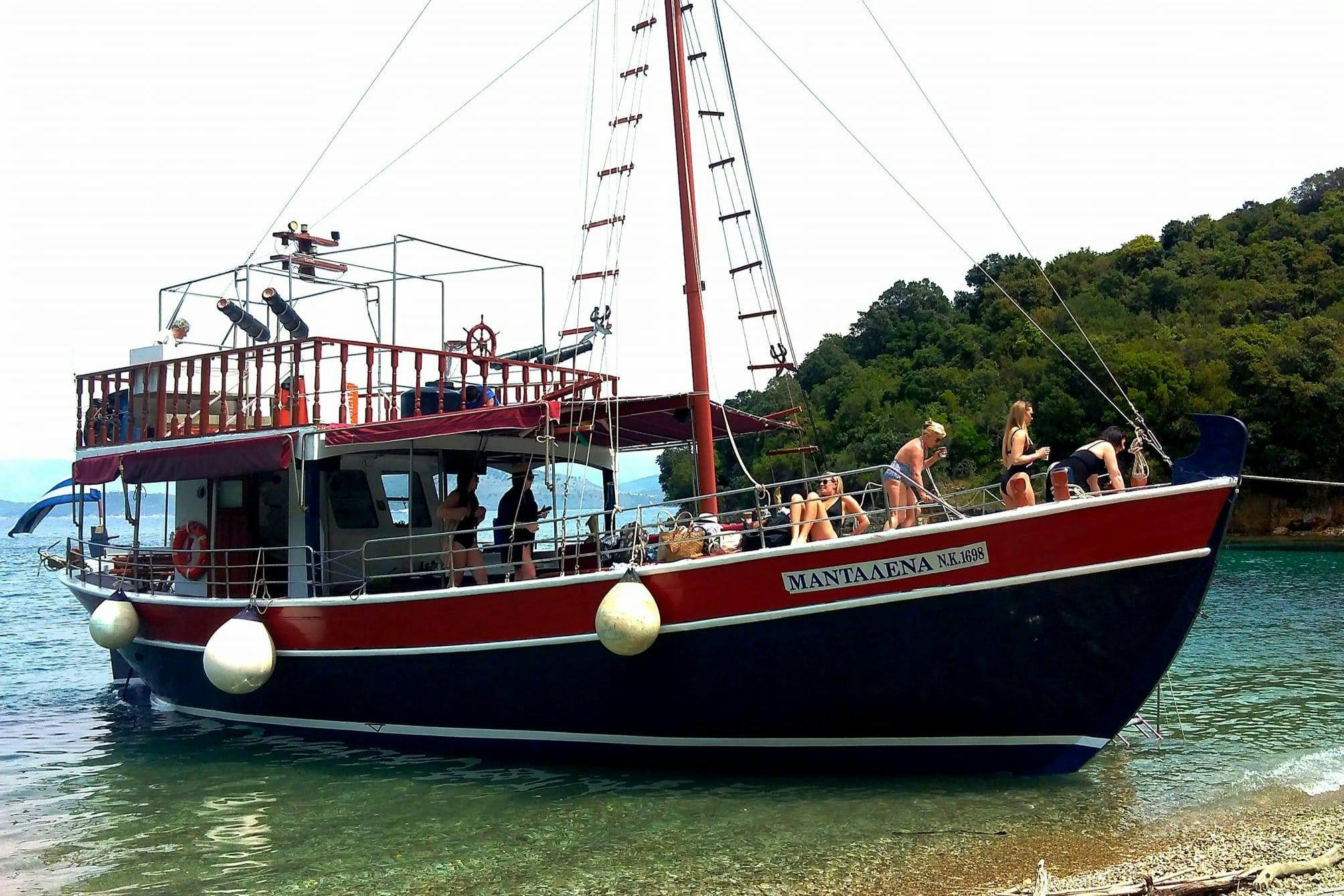 Una barca rossa e nera con persone che prendono il sole e si rilassano, ormeggiata vicino a un litorale boscoso.